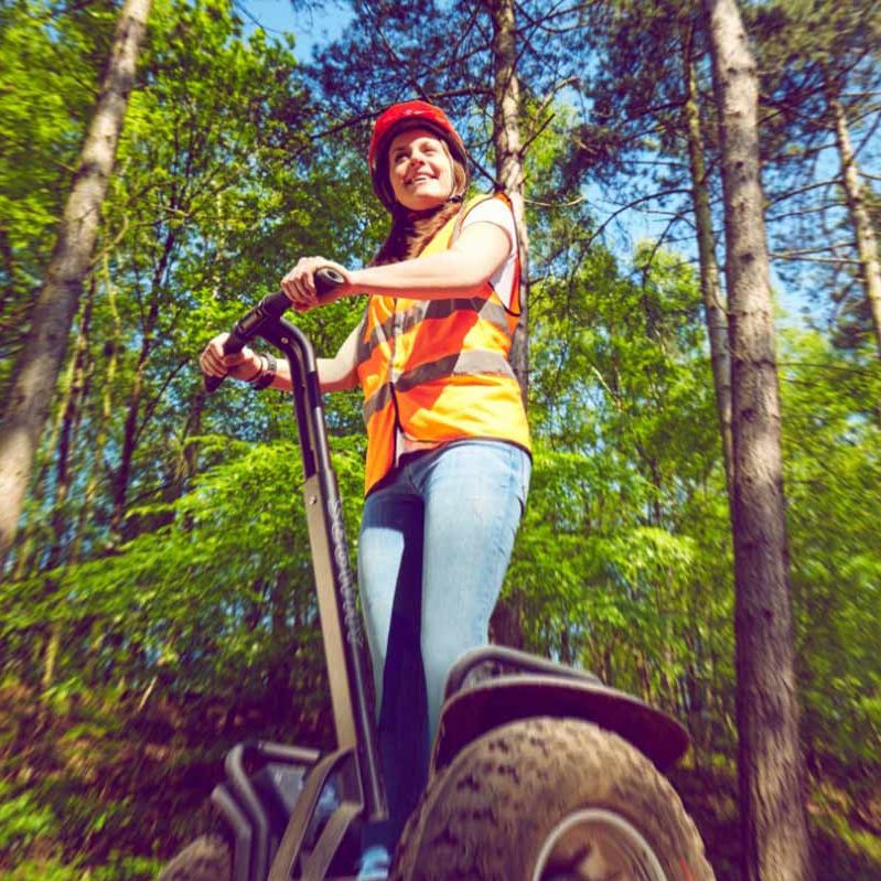 Two adults on a segway in the forest.