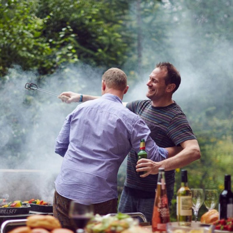 Two men hugging next to a BBQ