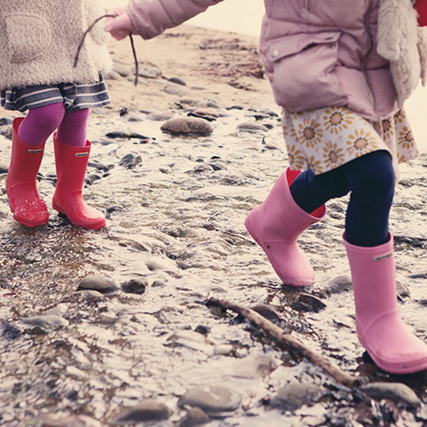 Children wearing Wellington Boots walking through puddles.