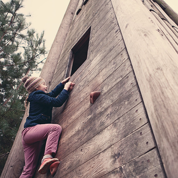 Girl climbs outdoor climbing wall
