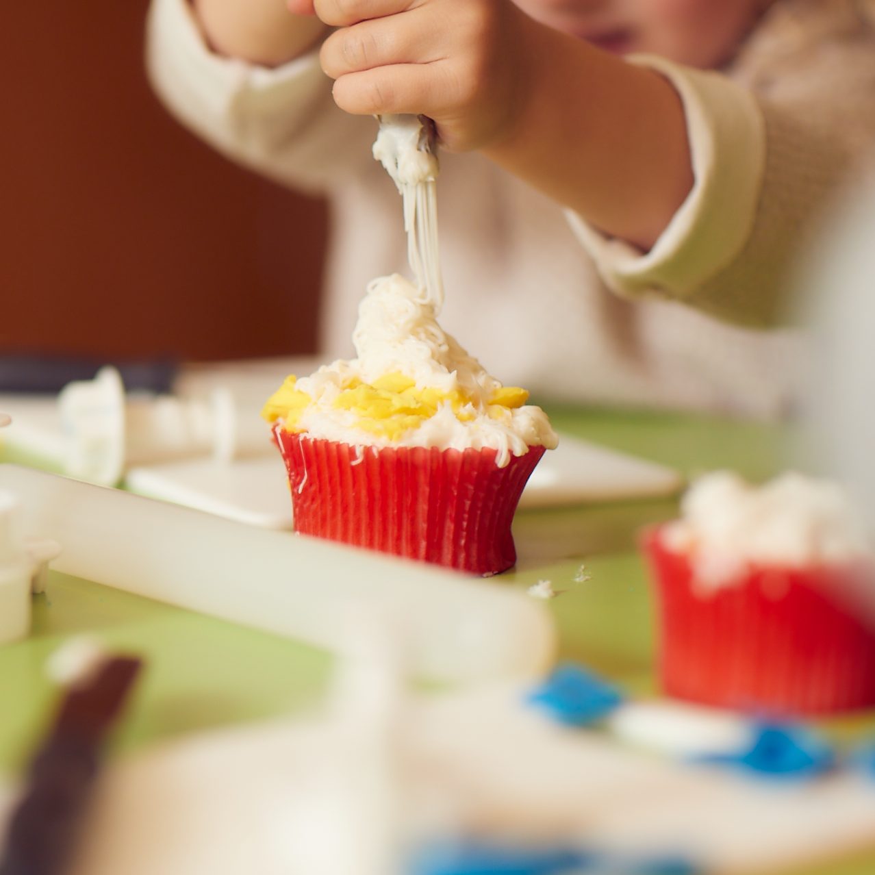 A little girl decorating a cupcake