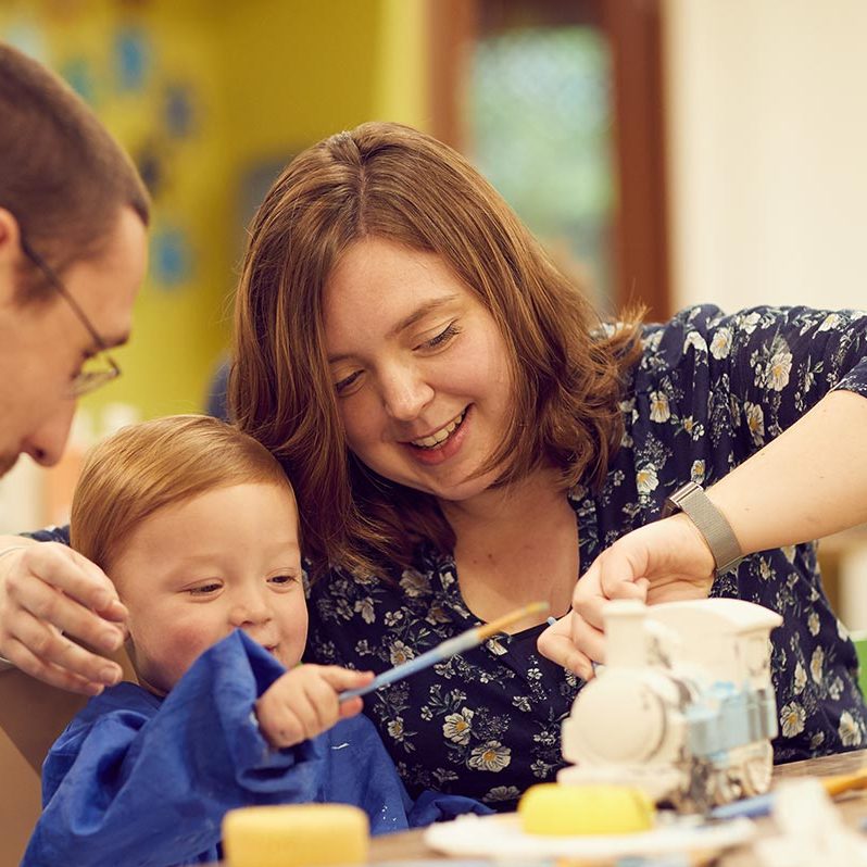A little boy and his parents doing pottery painting together