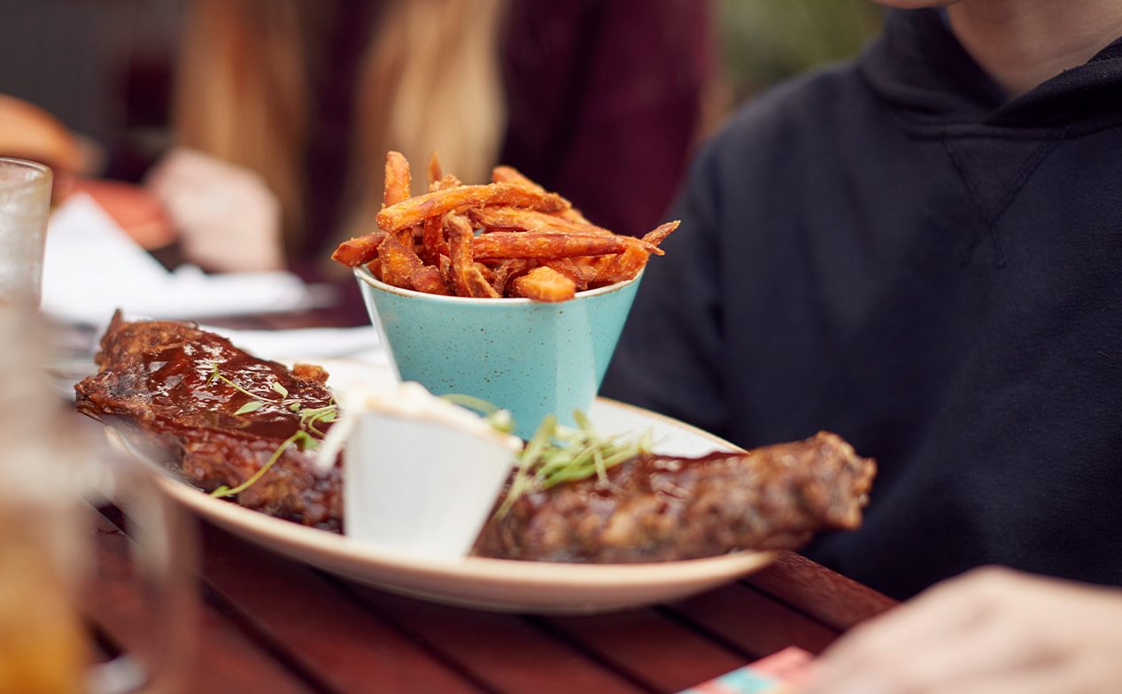 A close up of rack of ribs and a bowl of sweet potato fries