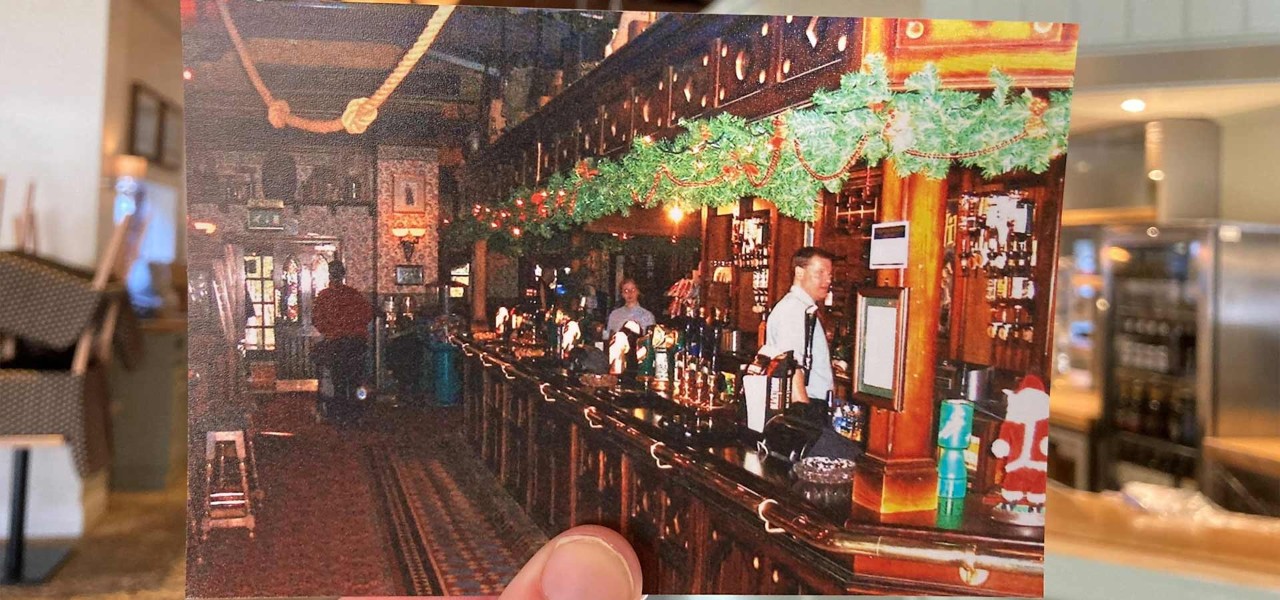 A hand holding up a photo of a bar decorated for winter