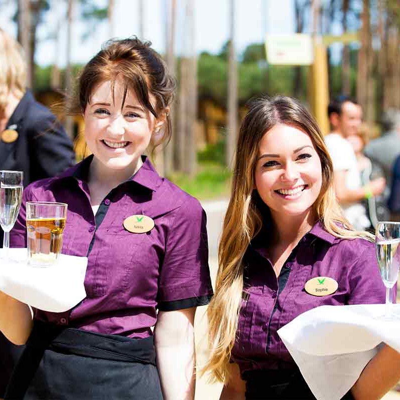 Two smiling female staff members holding drinks