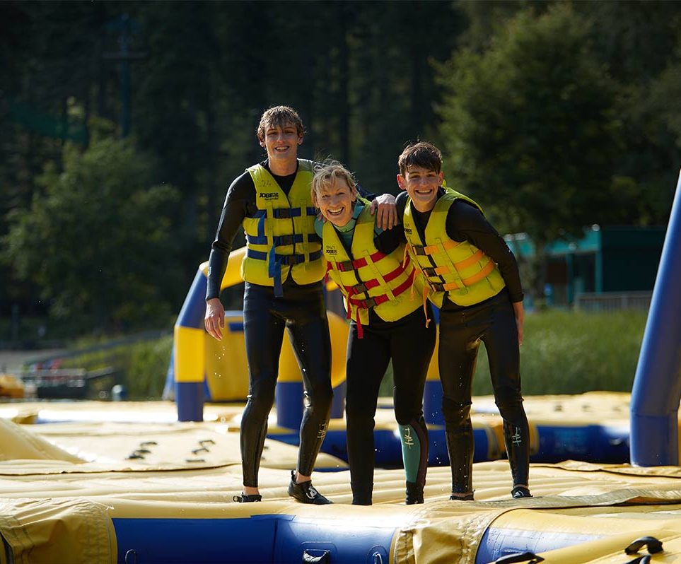 A mum and two sons on Aqua Parc, an inflatable obstacle course on the lake