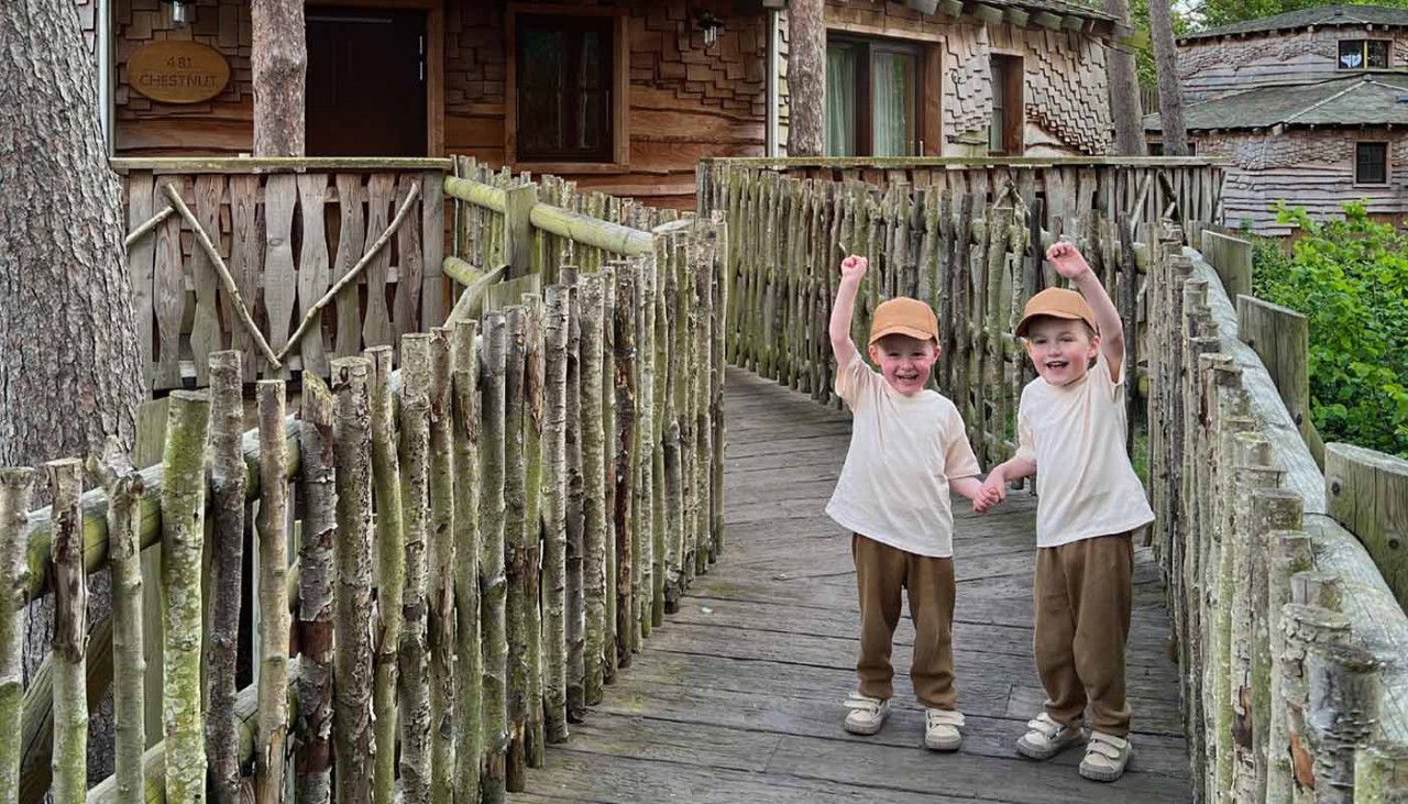 Two boys waving outside of a treehouse 